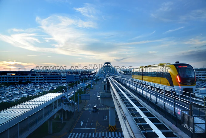 인천국제공항 주차장과 도로, 옆 선로의 노란 열차가 함께 보이는 전경